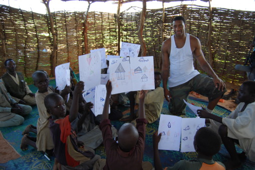 Tracy McGrady meeting with children in the camp. They are showing him drawings of how they remembered their homes being attacked. Photo: Darfur Dream Team